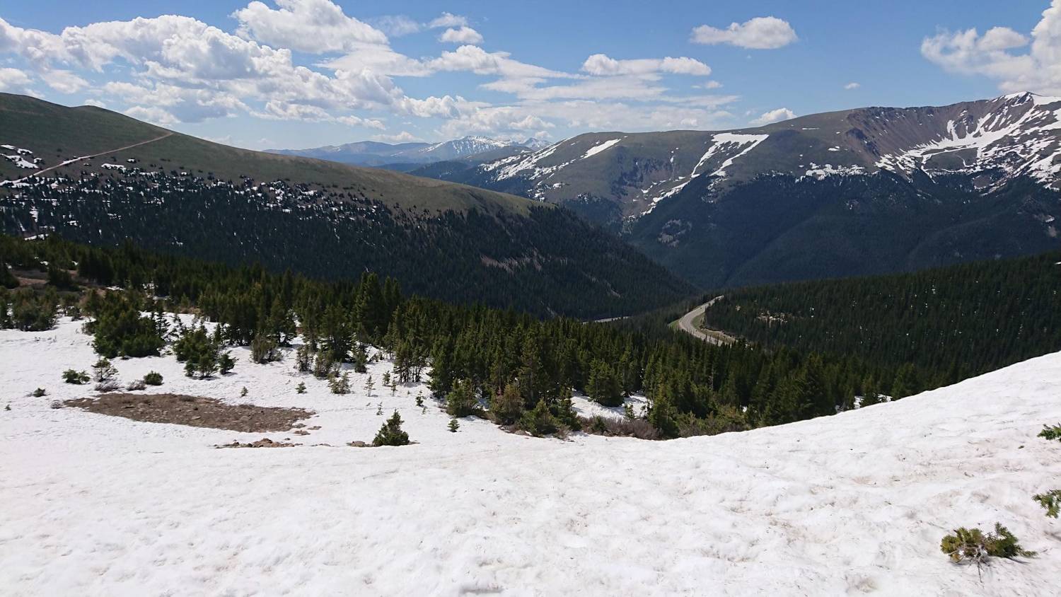 View looking down on a valley. The ground is covered in thick snow drifts.
